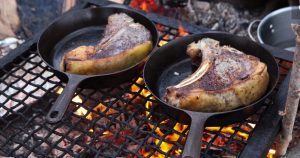 CastIronWSteaksOnCampfire The Best Cast Iron Skillet: How Much Should You Spend?